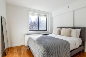 a white bedroom with a large bed and a window at Chelsea 1br w doorman gym nr Flatiron NYC-1320 in New York