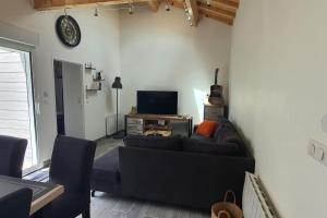 ein Wohnzimmer mit einem Sofa und einem TV in der Unterkunft Chai Callie, ancien Chai meublé in Cognac