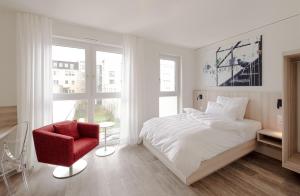 a bedroom with a white bed and a red chair at Mintrops Concierge Hotel in Essen