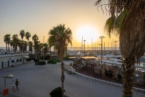 un coucher de soleil sur un port de plaisance avec des palmiers et des bâtiments dans l'établissement Marina Beach Hotel, à Tel Aviv
