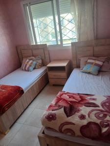 two beds in a room with two windows at Super appartement avec parking gratuit in Oujda
