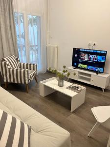 sala de estar con TV, sofá y mesa en Metropolitan Complex Apartment Faliro, en Pireo