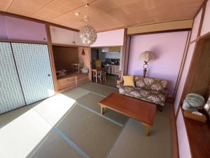a living room with a couch and a table at Guesthouse Papaya in Shimoda