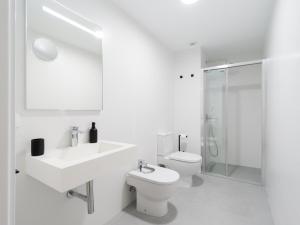 a white bathroom with a toilet and a sink at Sea City by CanariasGetaway in Las Palmas de Gran Canaria +34 photos