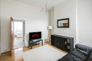 a living room with a couch and a television at Super Stylish 1BD Flat with Garden in Leytonstone in London