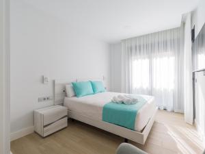 um quarto branco com uma cama com almofadas azuis em Urban Square 3A5 By CanariasGetaway em Las Palmas de Gran Canaria