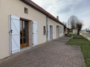 a white building with doors and a brick sidewalk at Maison Piscine et Jacuzzi in Saint-Germain-des-Fossés