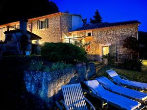 eine Gruppe von Liegestühlen und ein Haus in der Nacht in der Unterkunft B&B Podere Camaiano in Roccastrada