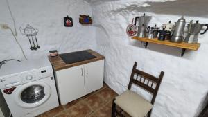 a laundry room with a washing machine and a chair at Cueva la Tita del Pan in Bácor