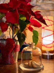 einen Tisch mit einer Vase mit roten Blumen und einem Glasgefäß in der Unterkunft B&B Podere Camaiano in Roccastrada