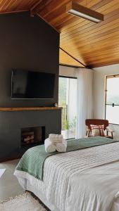 a bedroom with a bed with a fireplace and a flat screen tv at Encontro dos Vales in Visconde De Maua