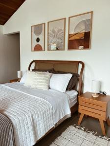 a bedroom with a bed with three pictures on the wall at Encontro dos Vales in Visconde De Maua