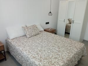 1 dormitorio con 1 cama con edredón gris y blanco en Maison neuve moderne en Los Baños