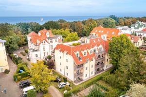 une vue aérienne sur un grand bâtiment blanc avec des toits orange dans l'établissement Strandnahe Fewo mit Balkon, WLAN-Anschluss & PKW-Stellplatz, à Kühlungsborn