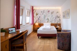 Zum Dallmayr Hotel Garni في برشينغ: غرفة نوم مع سرير ومكتب مع الكمبيوتر المحمول