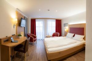 ベルヒングにあるZum Dallmayr Hotel Garniのベッドとデスクが備わるホテルルームです。