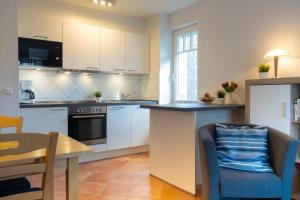 奥斯赛拜-屈隆斯博恩Schönes Apartment mit Balkon, Parkplatz, WLAN的厨房配有白色橱柜、桌子和椅子