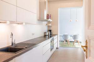 a kitchen with white cabinets and a sink at Großzügige Designer- Luxuswohnung für 2 Personen in stilvoller Altbauvilla in Heringsdorf