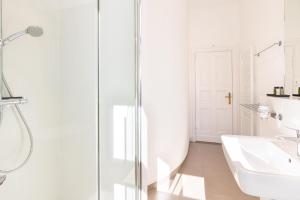 a white bathroom with a shower and a sink at Großzügige Designer- Luxuswohnung für 2 Personen in stilvoller Altbauvilla in Heringsdorf