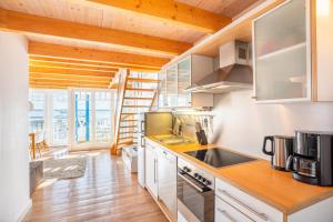 a kitchen with white cabinets and a wooden floor at Helle Fewo mit Salzhaffblick über 2 Ebenen in Rerik