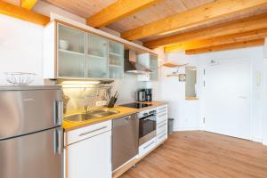 a kitchen with stainless steel appliances and wooden ceilings at Helle Fewo mit Salzhaffblick über 2 Ebenen in Rerik +8 photos