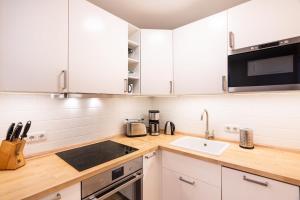 une cuisine avec des armoires blanches et un évier dans l'établissement Einladende Fewo mit Badewanne, Balkon, Boxspringbett, à Kühlungsborn