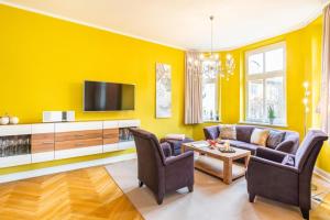 uma sala de estar amarela com um sofá e uma televisão em Großzügige Fewo mit Terrasse, Strandkorb em Bansin