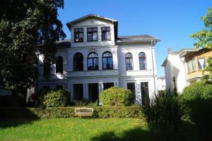 uma grande casa branca com um banco no quintal em Großzügige Fewo mit überdachter Terrasse, eigener Waschmaschine em Heringsdorf