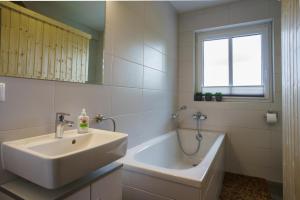 uma casa de banho branca com um lavatório e uma banheira em charmantes Ferienhaus für 4 Personen mit Sauna und 2 Bädern em Korswandt