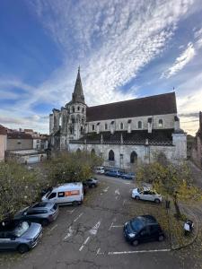 an old church with cars parked in a parking lot at Le Saint Eusèbe in Auxerre