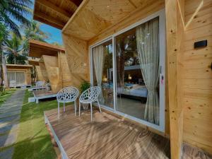 een houten huis met 2 stoelen en een slaapkamer bij The Nine Beach Resort in Canacona