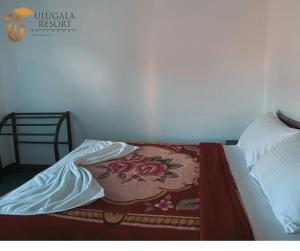 a bed with a blanket on top of it at Ulugala Resort in Nuwara Eliya