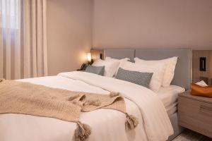 Viola Gardens Residence في الرياض: غرفة نوم بسرير كبير عليها شراشف ووسائد بيضاء