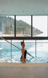 a woman sitting on a surfboard in the water at Hotel Pozzamanigoni in Selva di Val Gardena