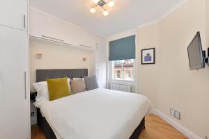 a bedroom with a large white bed with yellow pillows at Chiltern Street Serviced Apartments by Globe Apartments in London