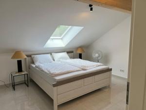 um quarto branco com uma cama com uma clarabóia em DG-Wohnung in Starnberg Nord em Starnberg