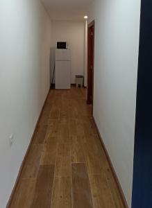 an empty room with a refrigerator and a wooden floor at Apartamento Puente Romano in Salamanca