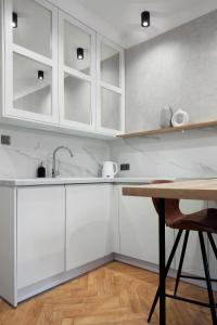 a kitchen with white cabinets and a wooden table at Elite Apartments Old Town Ogarna in Gdańsk
