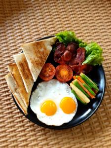 un plato de desayuno con huevos tocino y verduras en Eco Bamboo Island Bali - Bamboo House #3, en Selat