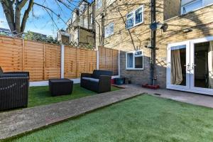 a backyard with a couch and chairs on the grass at Gorgeous Home in Islington in London