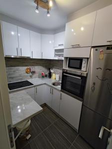 a kitchen with white cabinets and a stainless steel refrigerator at Stan na dan Apartman KRISFIL Prnjavor in Prnjavor