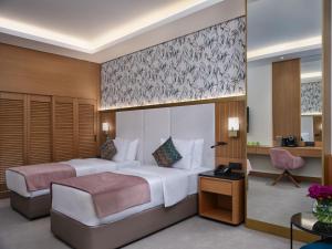 Habitación de hotel con 2 camas y escritorio en Qafqaz Riverside Hotel en Gabala