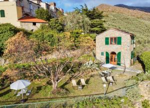 ein Haus auf einem Hügel mit Stühlen und einem Regenschirm in der Unterkunft Borgata Castello in Chiusanico