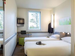 ロワシー・アン・フランスにあるイビス バジェット ロワシー CDG パリ ノード2のベッド2台とテレビが備わるホテルルームです。