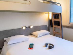 a bedroom with a bed with two phones on it at ibis budget Roissy CDG Paris Nord 2 in Roissy-en-France