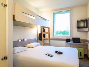 Un dormitorio con una litera con una cámara. en ibis budget Roissy CDG Paris Nord 2, en Roissy-en-France