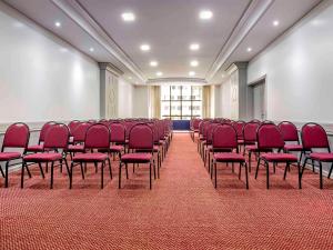 a large room with red chairs and a white wall at Mercure Curitiba 7 de Setembro in Curitiba