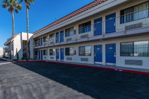 a building with blue doors and palm trees on a street at Rodeway Inn & Suites Thousand Palms - Rancho Mirage in Thousand Palms