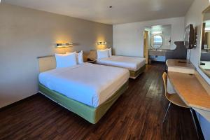 a hotel room with two beds and a desk at Rodeway Inn & Suites Thousand Palms - Rancho Mirage in Thousand Palms