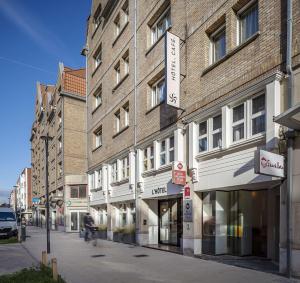 eine Person, die vor einem Gebäude Fahrrad fährt in der Unterkunft Best Western Plus Hotel Cargo in Dunkerque